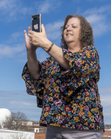 Tina Rogerson holds a cell phone vertically to take a photo. 